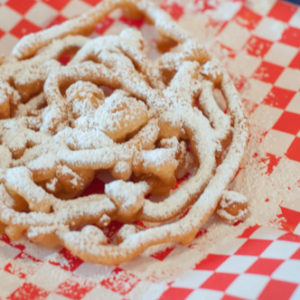 funnel cake with powdered sugar on red checked tissue