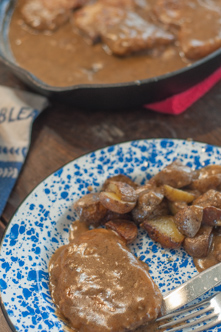 These Fried Smothered Pork Chops from Farmwife Feeds are an easy recipe using boneless chops that cook quickly and get supper on the table fast. #pork #castiron #gravy