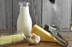 Ingredients for homemade Alfredo sauce including cream, Parmesan cheese, garlic, and butter on a rustic wood surface