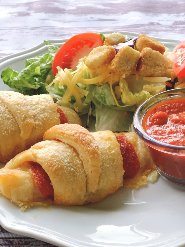 Easy pepperoni crescent roll calzones with mozzarella cheese, served with salad and marinara sauce - perfect kid-friendly meal