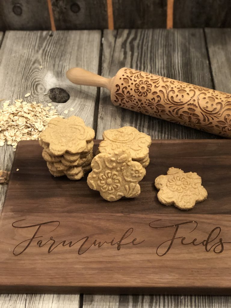 Stack of gluten free princess cookies with one cookie in front showing embossed design on wooden cutting board