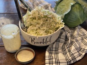 white bowl of cole slaw mason jar of dressing