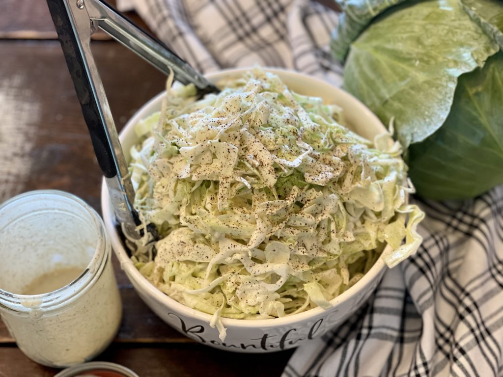 white bowl of cole slaw mason jar of dressing