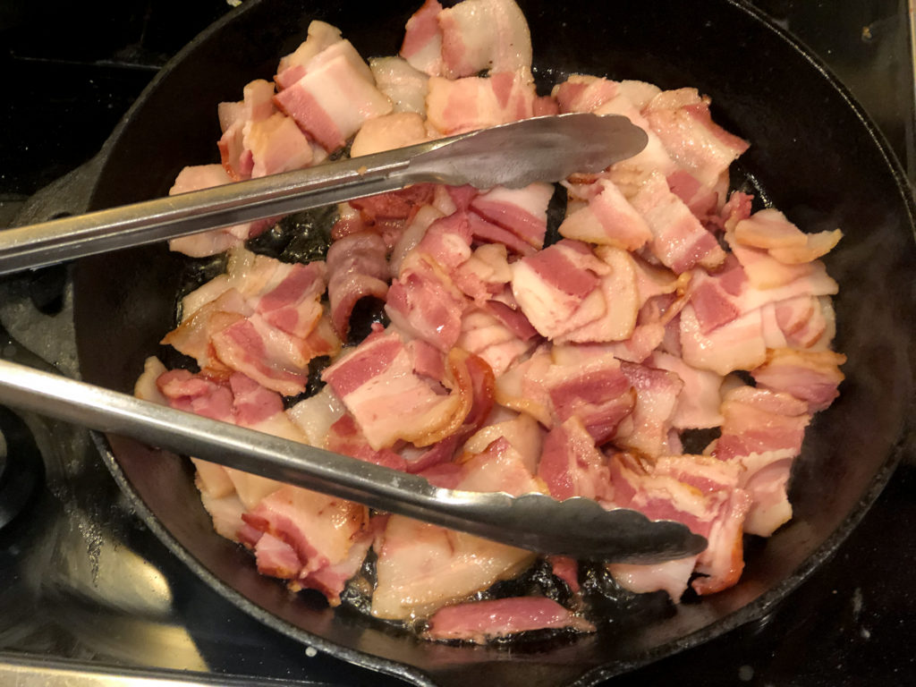 bacon frying in a cast iron skillet