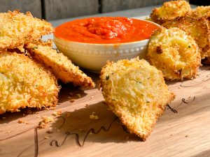 picture of crispy ravioli that has been air fryed with small bowl of marinara for dipping words