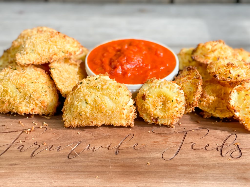 picture of crispy ravioli that has been air fryed with small bowl of marinara for dipping words