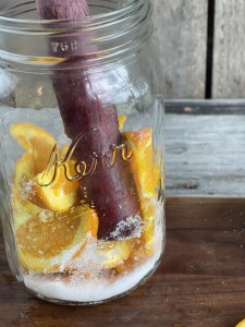 Close up of a glass with muddler working orange sliced and sugar for an Orange Shake-up