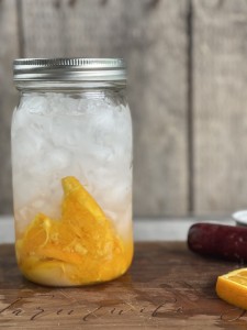 Mason jar of muddled orange slices, sugar and crushed ice to make a Orange Shake-up