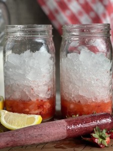 mason jar full of crushed ice with muddled strawberries in the bottom