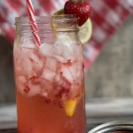 mason jar with ice, strawberries and lemon slices with straws