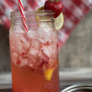 mason jar with ice, strawberries and lemon slices with straws
