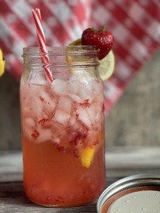 mason jar with ice, strawberries and lemon slices with straws