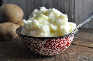 mashed potatoes with butter in serving bowl with whole potatoes