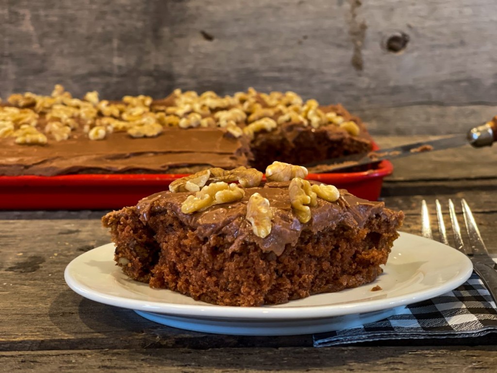 piece of chocolate Texas sheet cake with walnuts on top on a plate