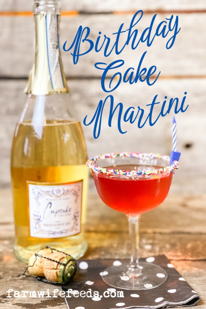 bottle of champagne prosecco with a glass of red cocktail sprinkles on glass rim and birthday candle with words Birthday Cake Martini