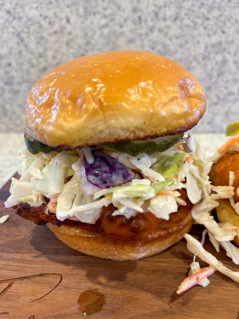 Air Fried Crispy Buffalo Chicken Breast sandwich topped with coleslaw and pickles on a toasted brioche bun