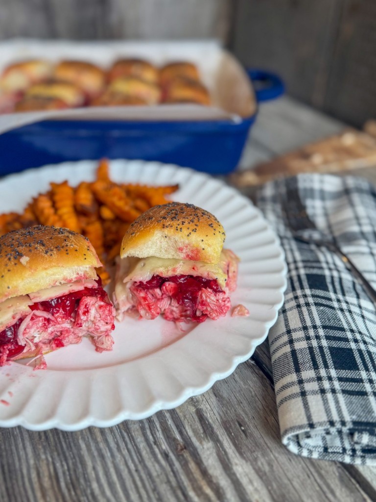 Turkey Cranberry Sliders served on a plate with sweet potato fries, showcasing layers of turkey, cranberry sauce, and melted cheese.