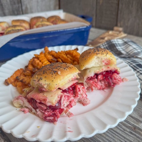 Turkey Cranberry Sliders served on a plate with sweet potato fries, showcasing layers of turkey, cranberry sauce, and melted cheese.