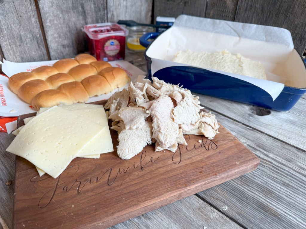 Ingredients for Turkey Cranberry Sliders: Hawaiian rolls, turkey, Havarti cheese, cranberry sauce, butter mixture, and a prepared baking dish.