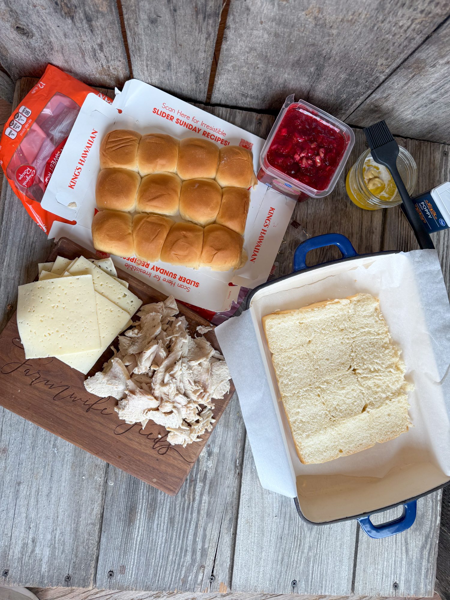 Ingredients for Turkey Cranberry Sliders: Hawaiian rolls, turkey, Havarti cheese, cranberry sauce, butter mixture, and a prepared baking dish.
