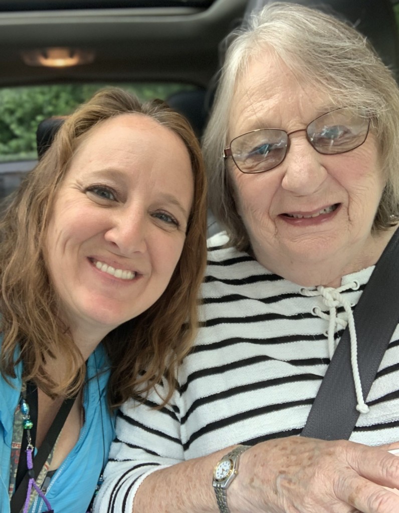 Daughter and mother smiling in a close-up selfie inside a car, showing their close relationship.