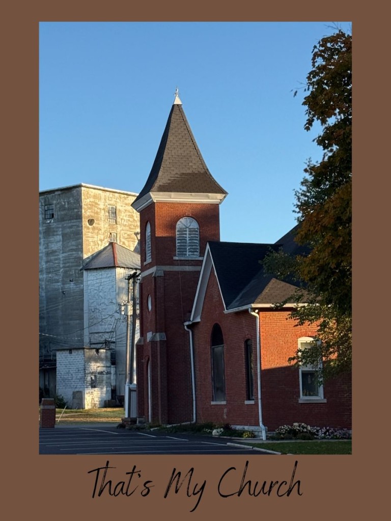 Red-brick country church at sunrise in rural Indiana with a tall steeple against a clear blue sky — a small-town landmark that symbolizes peace, tradition, and faith.