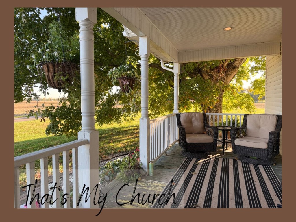 Peaceful farmhouse front porch with wicker chairs and hanging flower baskets overlooking fall fields in Indiana, a quiet space for prayer, reflection, and morning coffee.