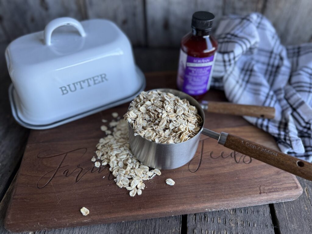 Rolled oats in measuring cup used to make oat flour for gluten free cookies with baking ingredients in background