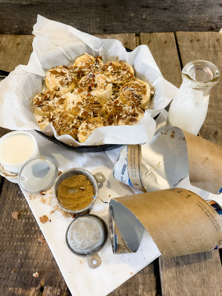 TikTok cinnamon rolls in a parchment lined cast iron skillet topped with brown sugar, heavy cream, and pecans before baking